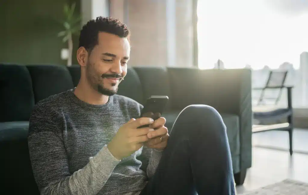 A man on his mobile phone sits in front of the couch