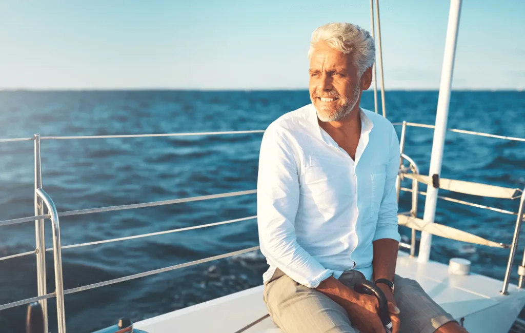 A man looks at the ocean while sitting on a boat.