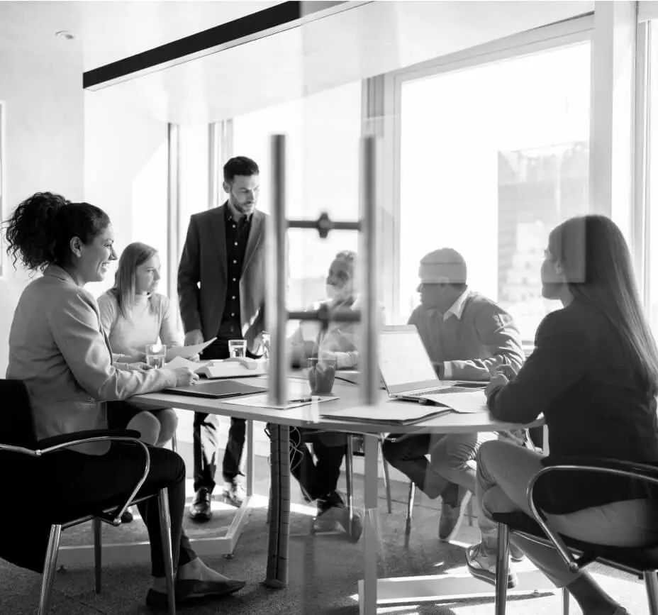 A man stands and discusses a topic in a meeting with colleagues