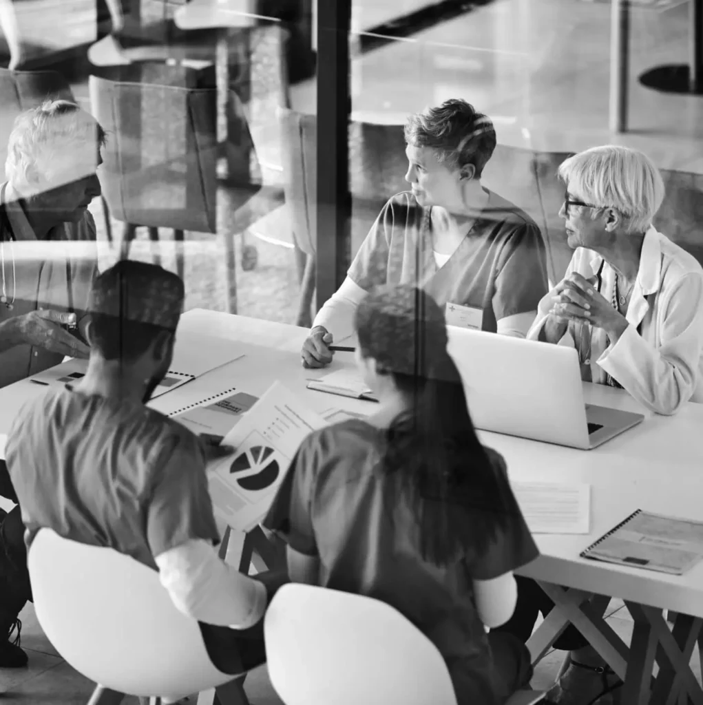 A group of colleagues sit around a table in a meeting.