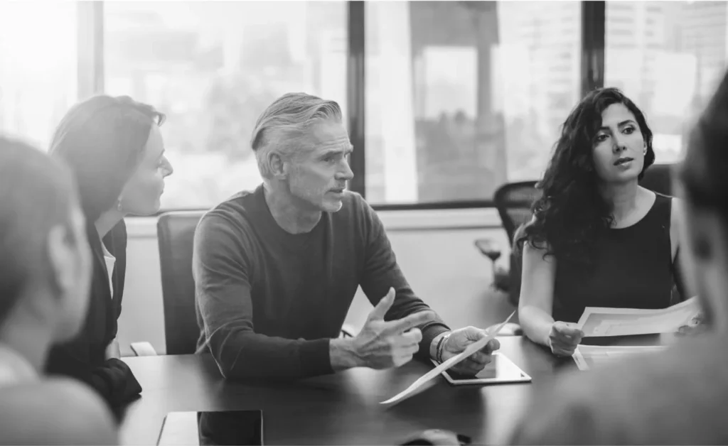 A man sits discusses a topic in a meeting with colleagues