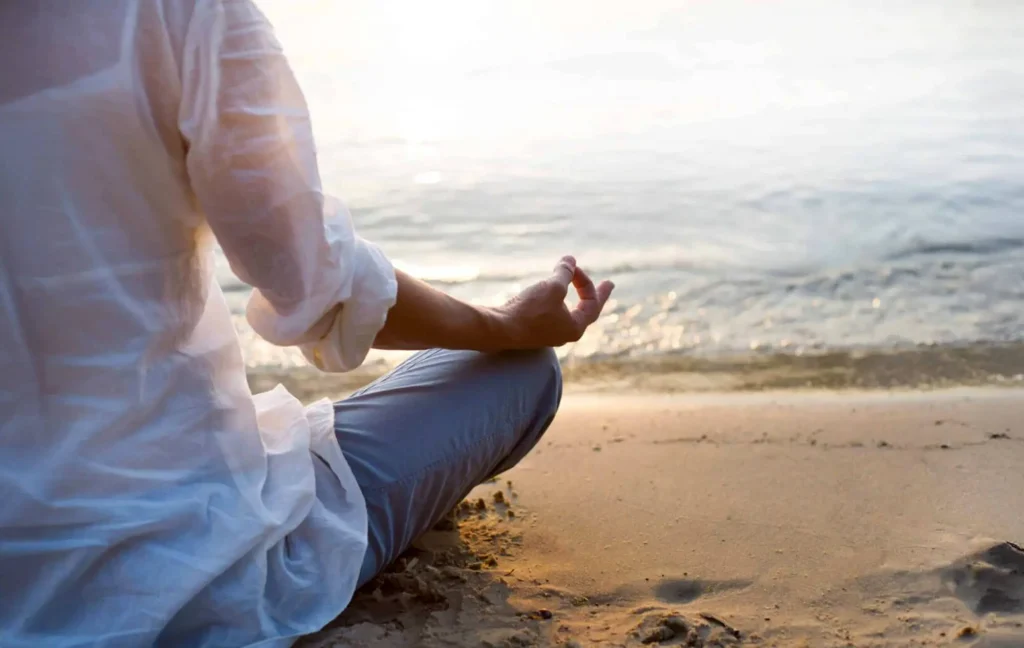 A person meditates on the beach.